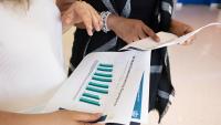 Two researchers look at bar graphs on paper.